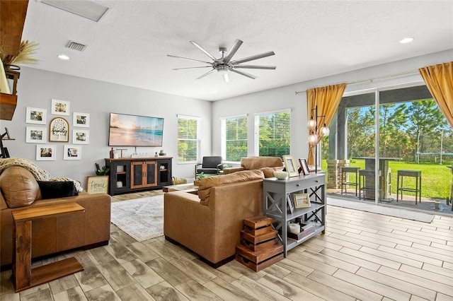 living room featuring a textured ceiling, light hardwood / wood-style flooring, and ceiling fan