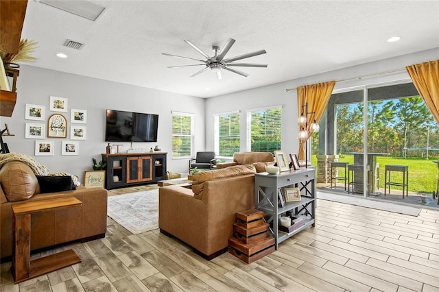 living room with ceiling fan, light hardwood / wood-style floors, and a textured ceiling