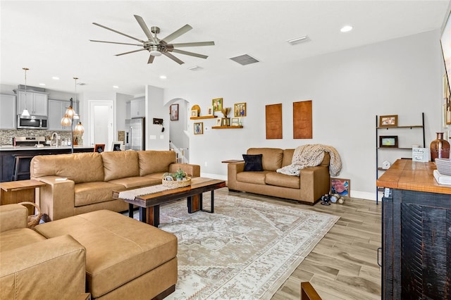 living room with light hardwood / wood-style floors, ceiling fan, and sink