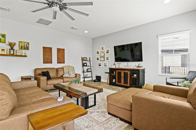 living room with ceiling fan, light hardwood / wood-style floors, and a textured ceiling