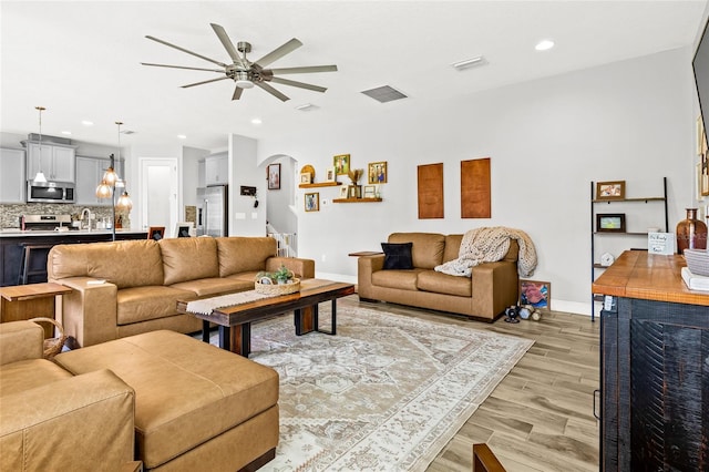 living room featuring ceiling fan, light hardwood / wood-style flooring, and sink