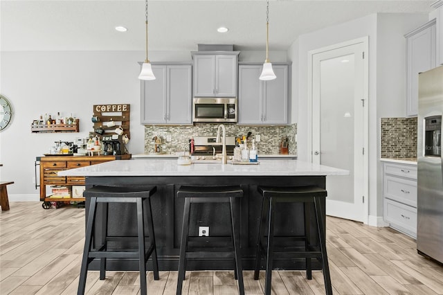 kitchen with pendant lighting, light wood-type flooring, and stainless steel appliances