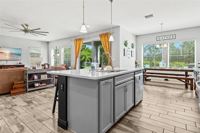 kitchen with a center island with sink, hanging light fixtures, gray cabinetry, and sink