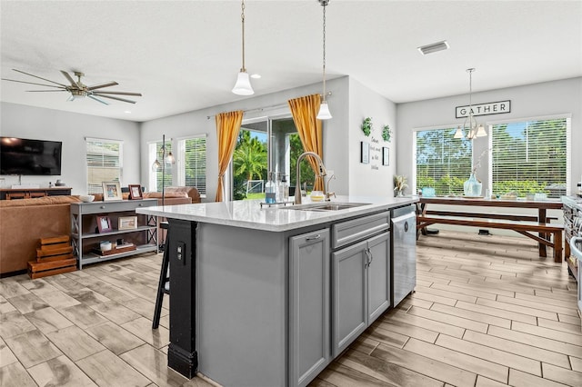 kitchen with gray cabinets, sink, a kitchen island with sink, and hanging light fixtures