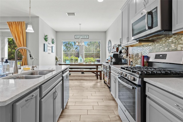 kitchen with decorative backsplash, appliances with stainless steel finishes, pendant lighting, and sink