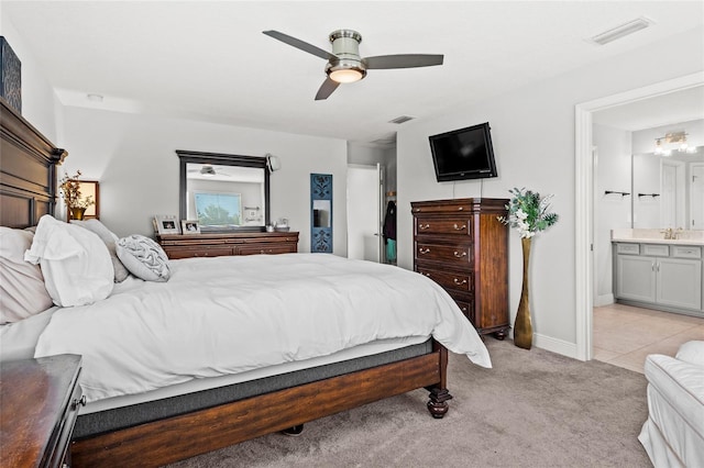 bedroom featuring light carpet, ensuite bath, and ceiling fan