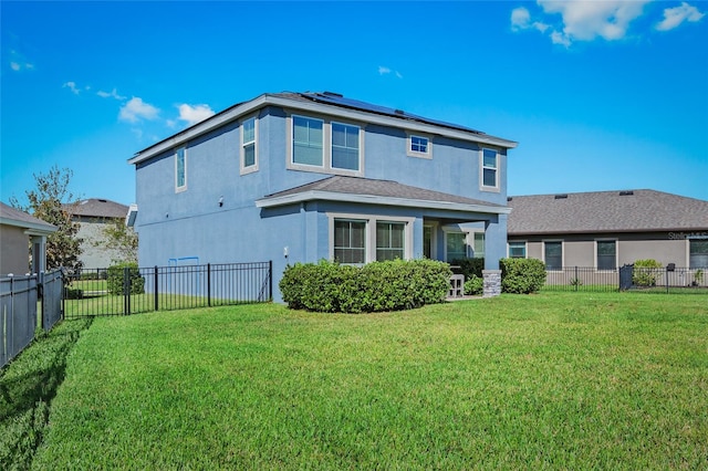 rear view of property with solar panels and a yard