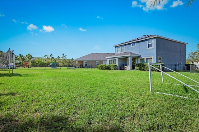 rear view of house featuring a yard and a trampoline