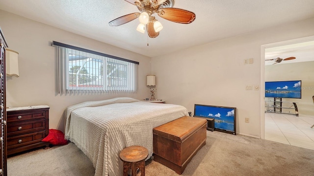 bedroom with a textured ceiling, light colored carpet, and ceiling fan