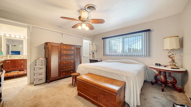 carpeted bedroom featuring a textured ceiling, ensuite bathroom, and ceiling fan