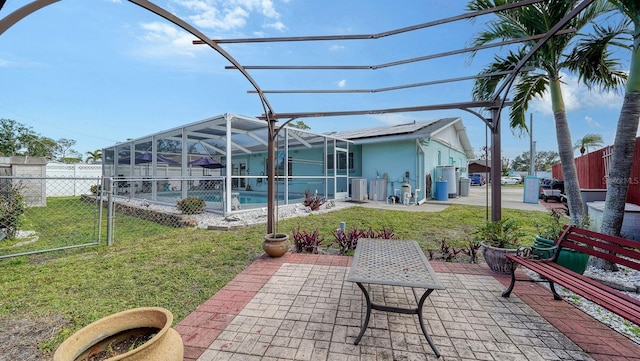 rear view of property featuring glass enclosure, a patio area, a fenced in pool, and a yard