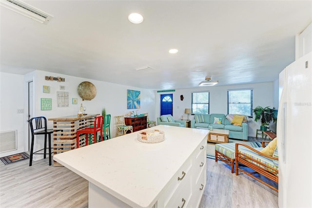 kitchen featuring a wall mounted AC, white cabinetry, a kitchen island, and light hardwood / wood-style floors