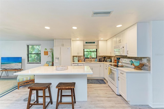 kitchen featuring white cabinets, light wood-type flooring, white appliances, and a wealth of natural light