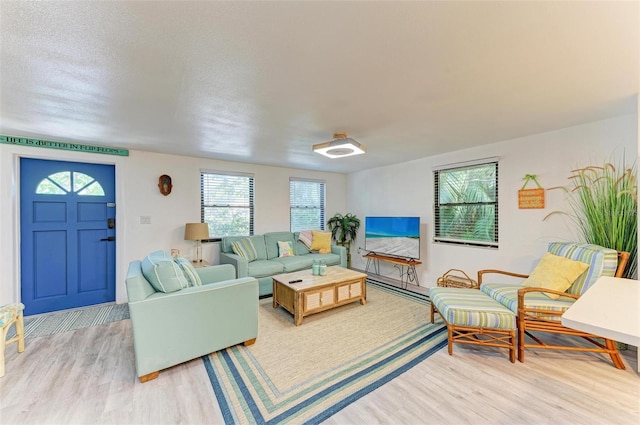 living room featuring light hardwood / wood-style flooring, a baseboard radiator, and a textured ceiling