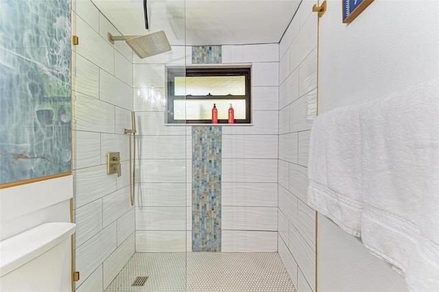 bathroom with tiled shower and toilet