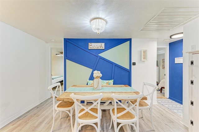 dining area with light hardwood / wood-style flooring and a textured ceiling