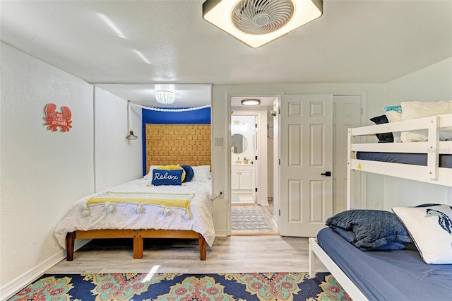 bedroom featuring light wood-type flooring and ensuite bath