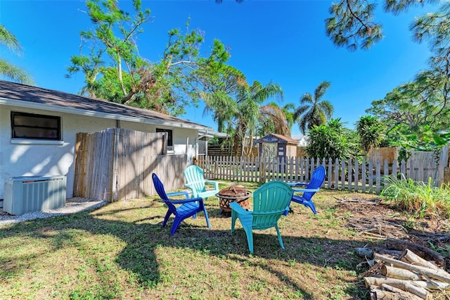 view of yard with a fire pit and central air condition unit