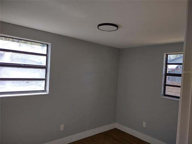 empty room featuring a healthy amount of sunlight and dark wood-type flooring