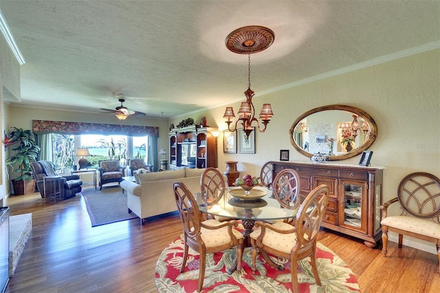 dining room featuring a textured ceiling, ornamental molding, ceiling fan with notable chandelier, and hardwood / wood-style flooring