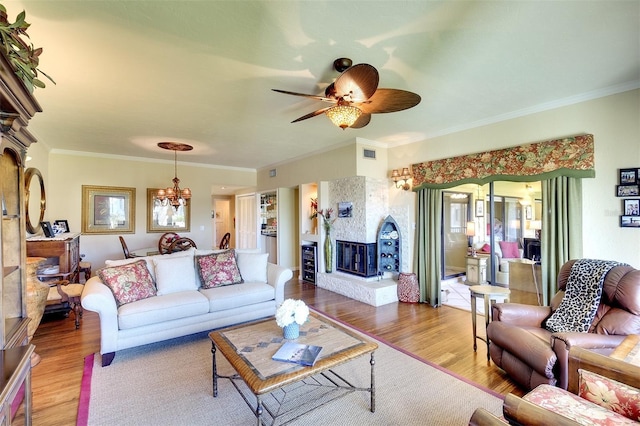 living room featuring hardwood / wood-style floors, ceiling fan with notable chandelier, and crown molding