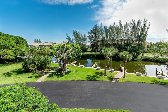 view of property's community with a yard, a dock, and a water view