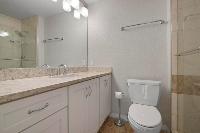 bathroom featuring vanity, tiled shower, and toilet