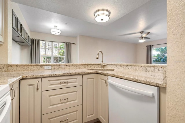 kitchen featuring sink, ceiling fan, light stone counters, white dishwasher, and a textured ceiling