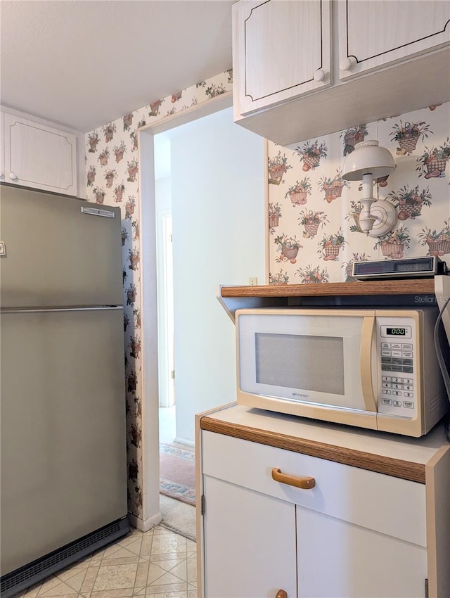 2228 Canal Dr Unit D26, Bradenton, FL 34207 - kitchen featuring freestanding refrigerator, white microwave, wallpapered walls, and white cabinetry
