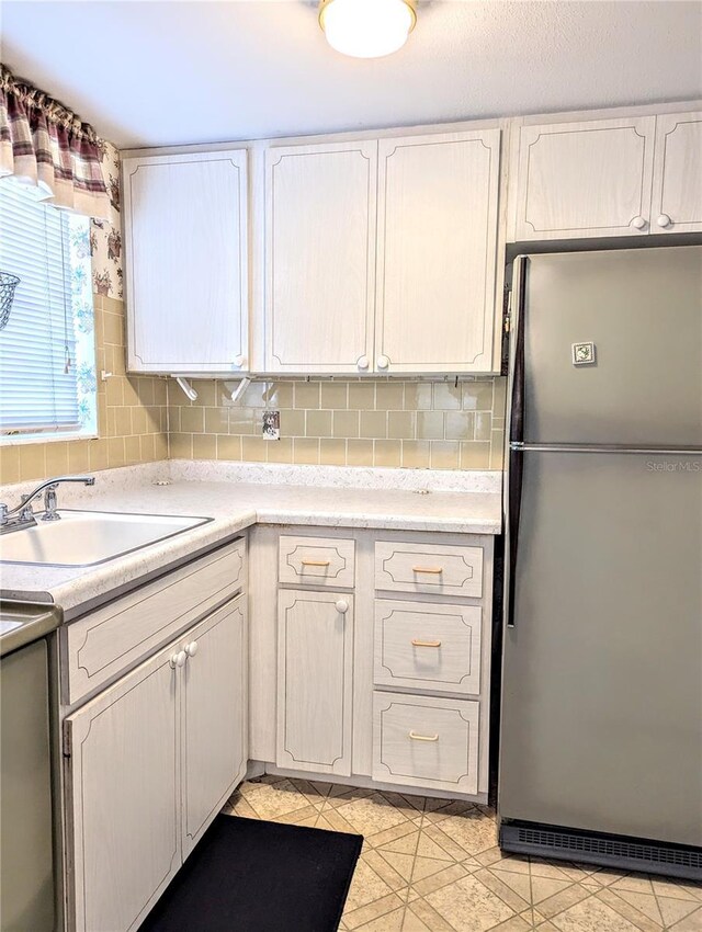 2228 Canal Dr Unit D26, Bradenton, FL 34207 - kitchen featuring freestanding refrigerator, light countertops, white cabinets, and tasteful backsplash