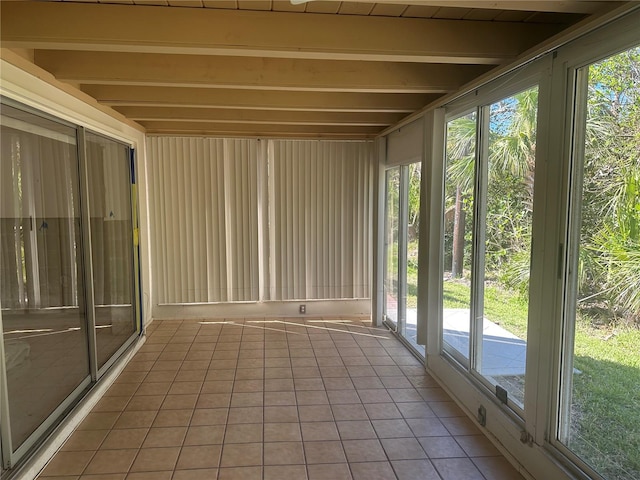 unfurnished sunroom featuring beamed ceiling and a healthy amount of sunlight