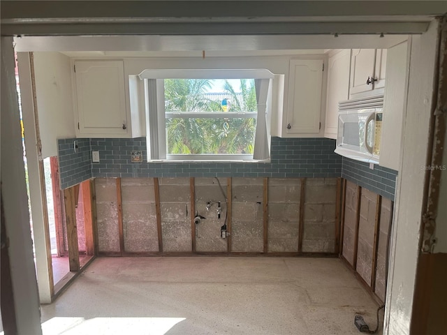 kitchen with tasteful backsplash and white cabinets