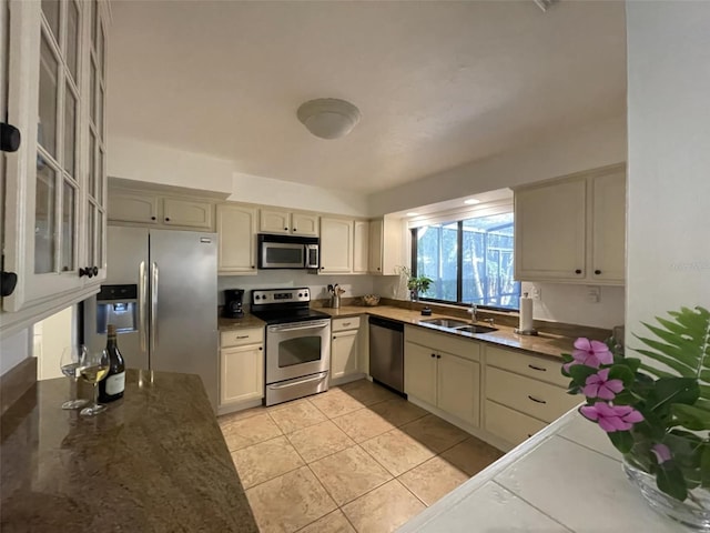 kitchen with sink, light tile patterned floors, cream cabinetry, and appliances with stainless steel finishes