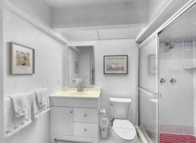 bathroom featuring vanity, a shower with shower door, and toilet