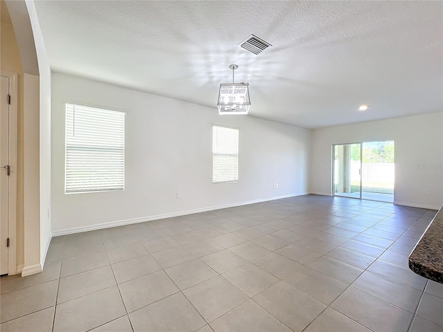 spare room featuring light tile patterned flooring and a textured ceiling