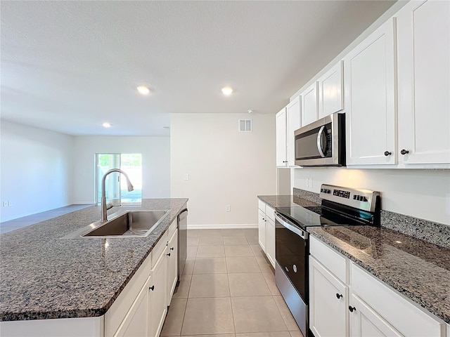 kitchen with white cabinetry, sink, stainless steel appliances, an island with sink, and light tile patterned flooring