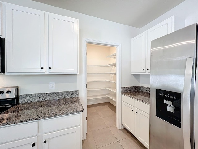 kitchen featuring white cabinets, stainless steel refrigerator with ice dispenser, dark stone counters, and light tile patterned flooring