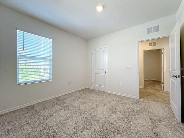 unfurnished bedroom with light colored carpet and a closet