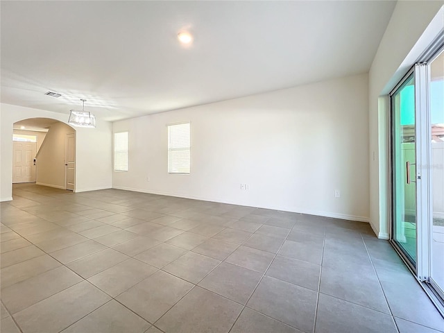 unfurnished room with a notable chandelier and light tile patterned flooring