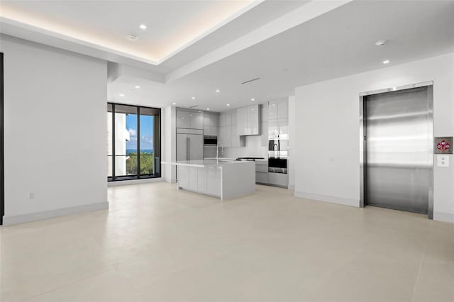 kitchen with white cabinets, a center island, sink, and elevator