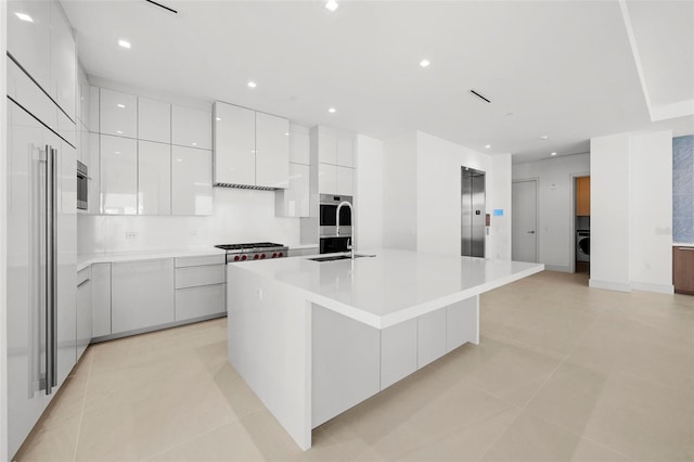 kitchen with elevator, sink, a spacious island, decorative backsplash, and white cabinets