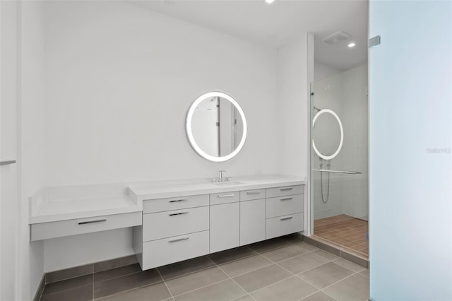 bathroom with a tile shower, vanity, and tile patterned floors