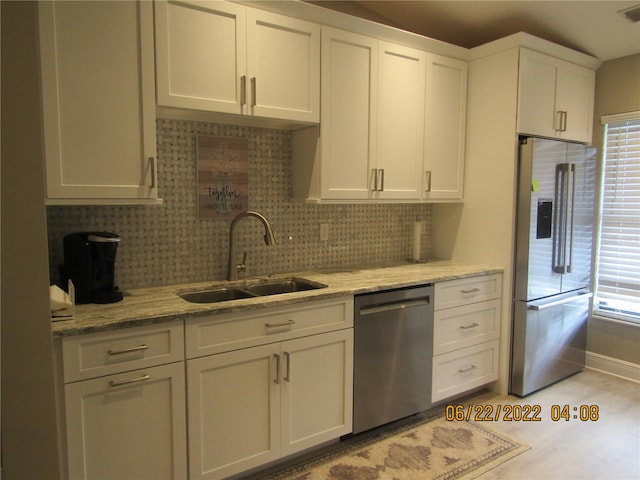 kitchen with sink, decorative backsplash, appliances with stainless steel finishes, light stone counters, and white cabinetry