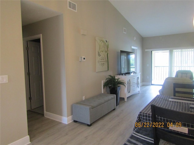 living room with light wood-type flooring and high vaulted ceiling