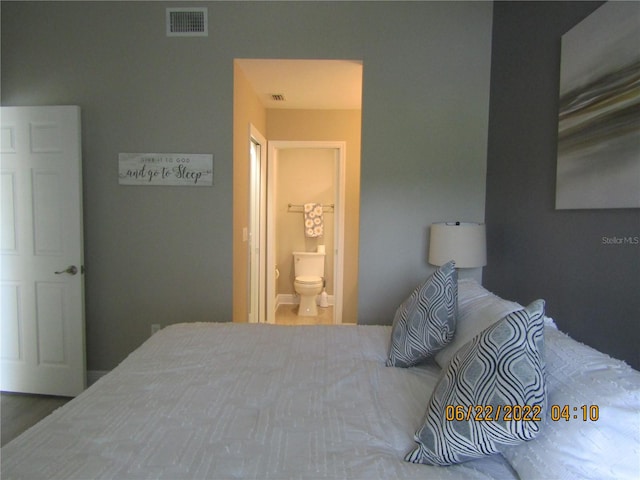 bedroom with hardwood / wood-style floors and connected bathroom