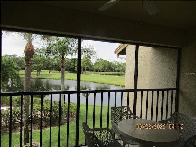 sunroom featuring a water view and ceiling fan