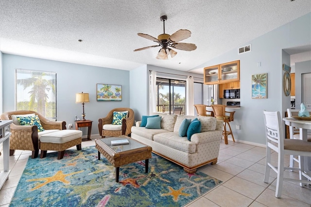 tiled living room with ceiling fan, lofted ceiling, and a textured ceiling