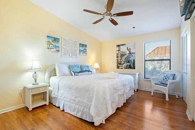 bedroom featuring wood-type flooring, vaulted ceiling, multiple windows, and ceiling fan