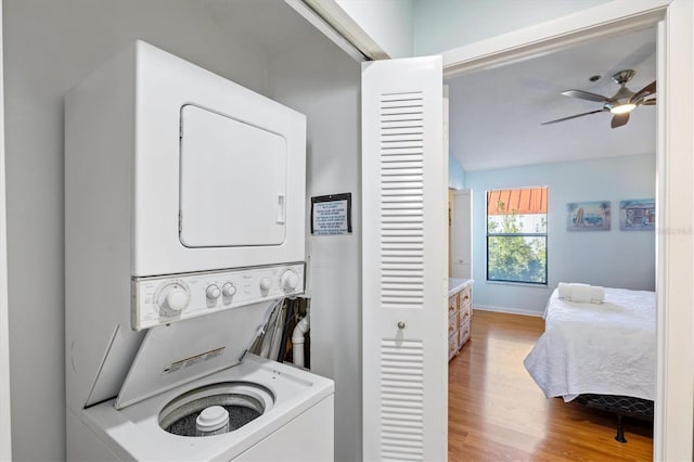 laundry area featuring stacked washing maching and dryer, light hardwood / wood-style flooring, and ceiling fan