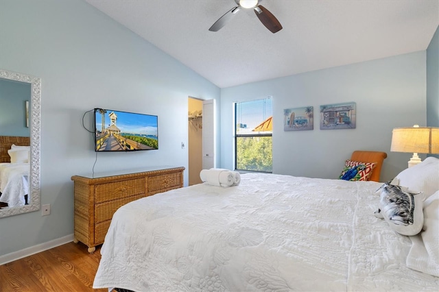 bedroom featuring ceiling fan, vaulted ceiling, a walk in closet, a closet, and hardwood / wood-style flooring